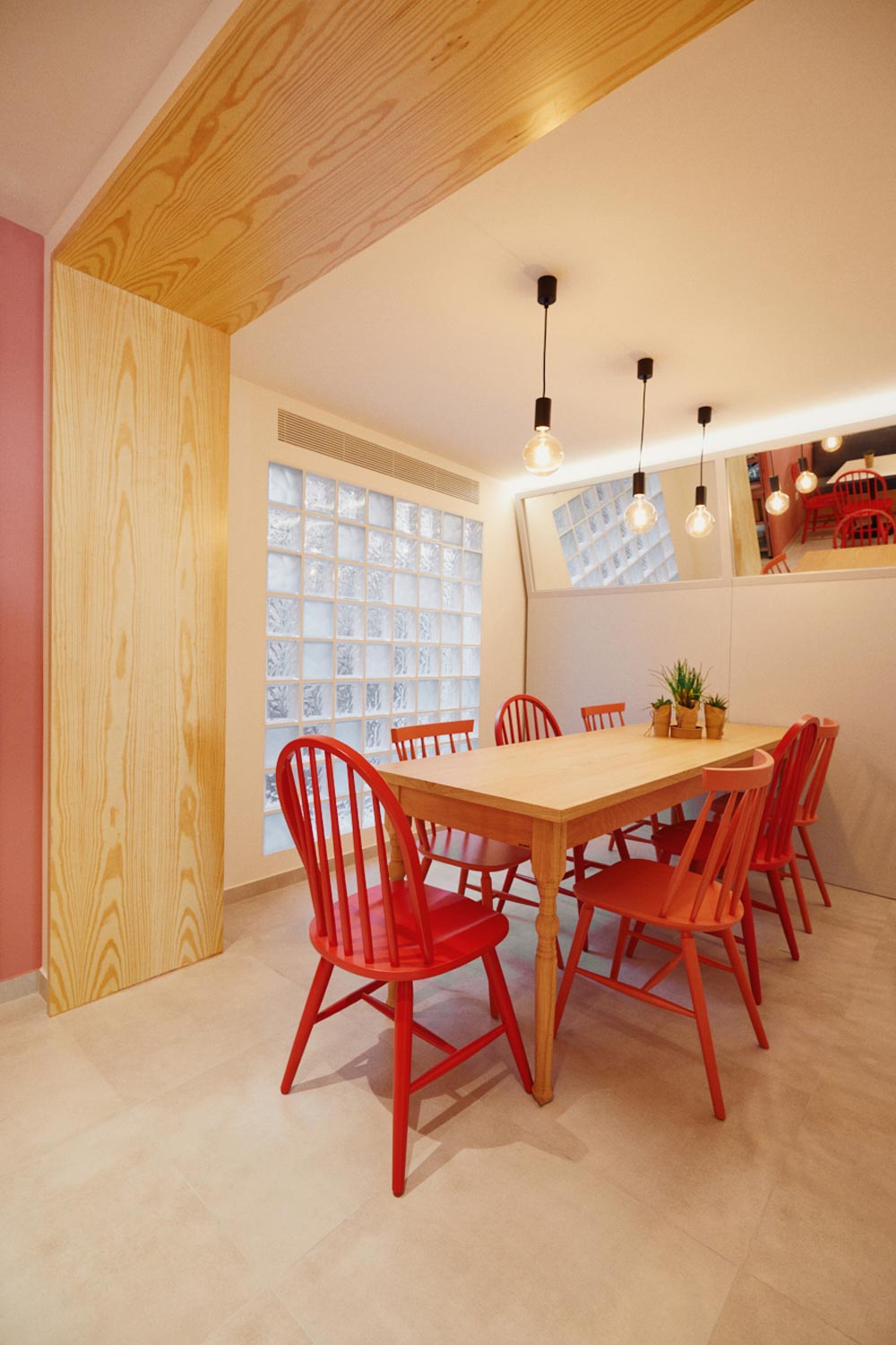 Brunch shop interior, view of the dining area with wooden table, red chairs and a mirror structure.